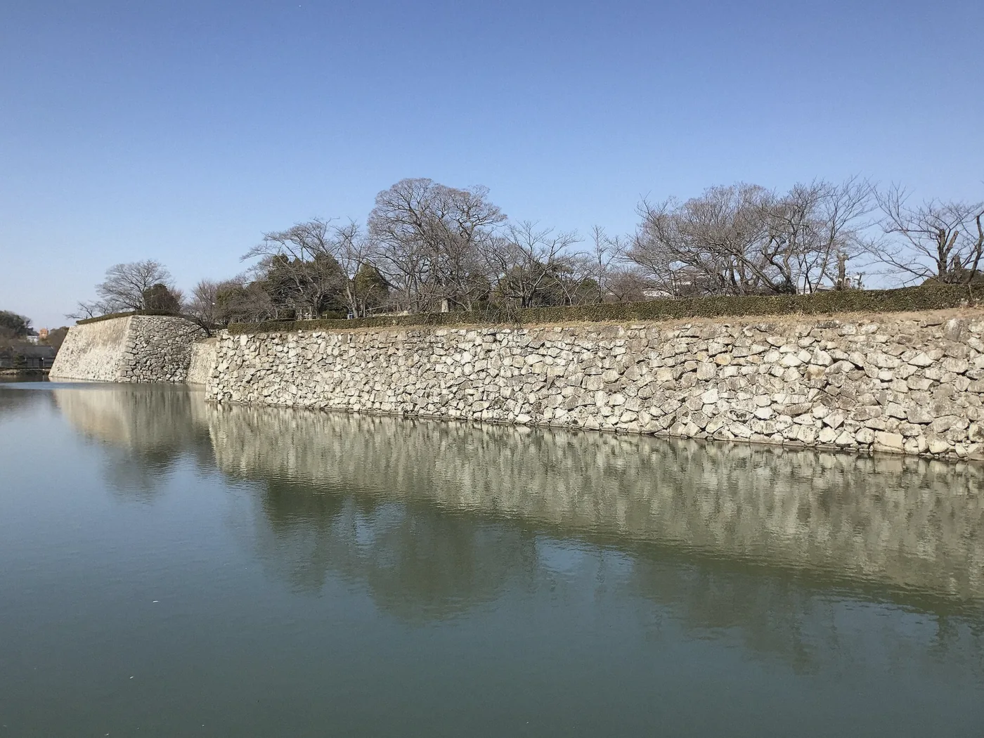 Stone walls of Himeji Castle rising from the moat, Japan